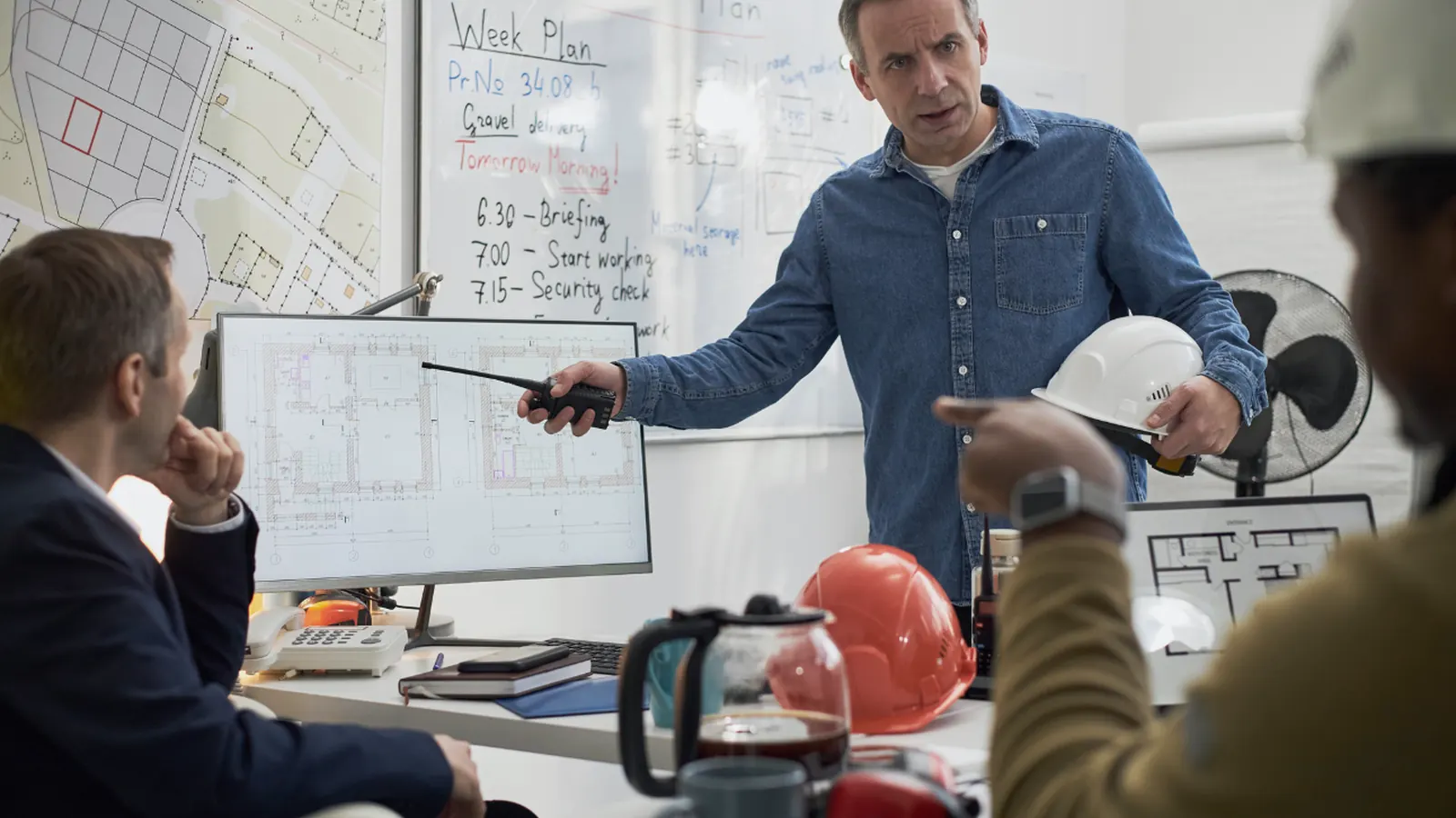 Réunion autour d'une table dans un bureau, avec un casque de chantier