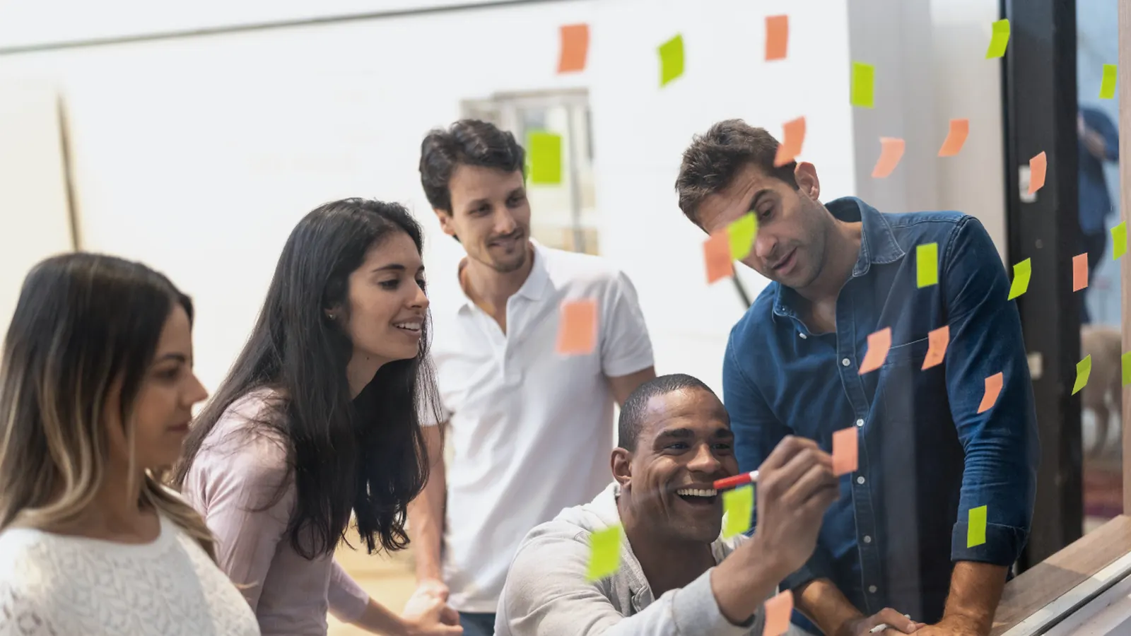 Équipe devant une paroi vitrée couverte de post-it